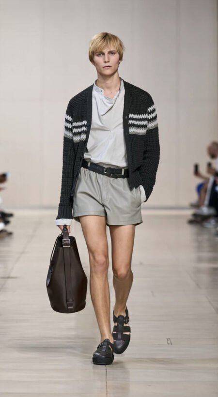 Model walking down the runway in shorts and a cardigan.