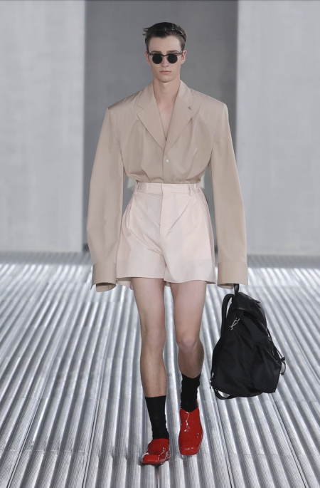 Model walking on the runway at Prada in high-waisted shorts and a tucked in blazer.